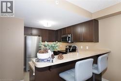 Kitchen featuring dark brown cabinets,  stainless steel appliances. and a breakfast bar. - 