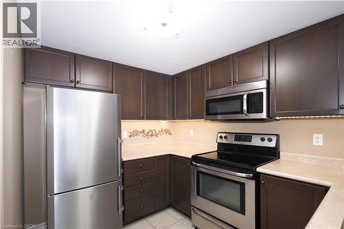 Kitchen with stainless steel appliances, dark brown cabinets, and light countertops - 645 St. David Street S Unit# 412, Fergus, ON - Indoor Photo Showing Kitchen