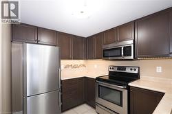 Kitchen with stainless steel appliances, dark brown cabinets, and light countertops - 