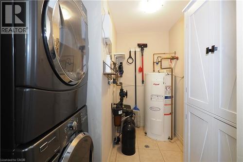 Laundry/utility room with electric water heater, stacked washer and dryer, and water softener - 645 St. David Street S Unit# 412, Fergus, ON - Indoor Photo Showing Laundry Room