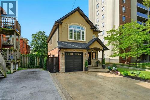 View of front of property with stucco siding, concrete driveway, an attached garage, and a shingled roof - 199 Hunter Street W, Hamilton, ON - Outdoor