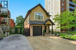 View of front of property with stucco siding, concrete driveway, an attached garage, and a shingled roof - 