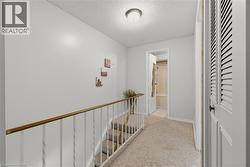 Hall with a textured ceiling, an upstairs landing, and light colored carpet - 