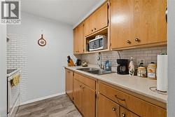 Kitchen with light countertops, decorative backsplash, white appliances, and brown cabinets - 