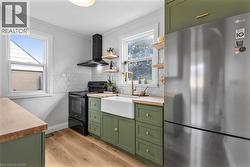 Kitchen featuring green cabinets, butcher block counters, freestanding refrigerator, and open shelves - 