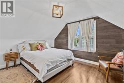 Bedroom featuring hardwood / wood-style floors, a textured ceiling, lofted ceiling, and wooden walls - 