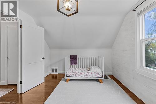 Bedroom featuring vaulted ceiling, a crib, and wood finished floors - 191 East 11Th Street, Hamilton, ON - Indoor Photo Showing Bedroom