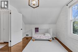 Bedroom featuring vaulted ceiling, a crib, and wood finished floors - 