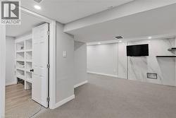 Finished basement with recessed lighting and light carpet - 