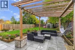 Fenced backyard featuring a storage unit, a patio, outdoor lounge area, a pergola, and a garden - 