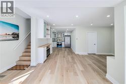 Unfurnished living room featuring light wood-type flooring, recessed lighting, and stairway - 
