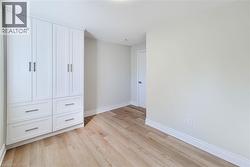 Unfurnished bedroom with baseboards and light wood finished floors - 