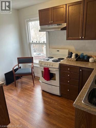 Kitchen featuring white electric range, ventilation hood, and dark brown cabinets - 37 Dundas Street, Dundas, ON - Indoor Photo Showing Kitchen