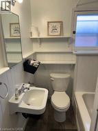 Bathroom with a wainscoted wall, dark wood-style floors, and a tub to relax in - 