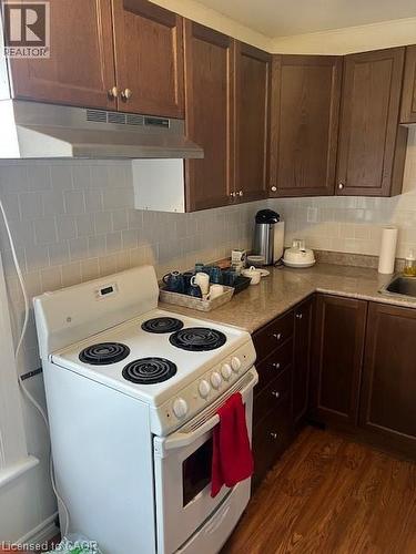 Kitchen featuring white stove, exhaust hood, dark wood finished floors, dark brown cabinets, and tasteful backsplash - 37 Dundas Street, Dundas, ON - Indoor Photo Showing Kitchen
