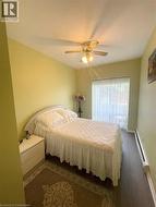 Bedroom featuring baseboard heating, wood finished floors, and a ceiling fan - 