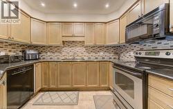 Kitchen featuring black appliances, decorative backsplash, light tile patterned flooring, and recessed lighting - 
