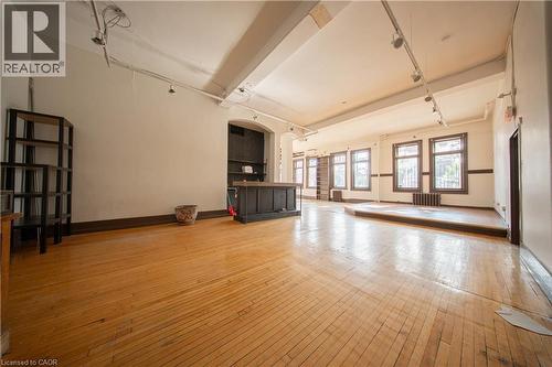 Unfurnished living room featuring light wood-style flooring and radiator heating unit - 231 Bay Street N, Hamilton, ON 