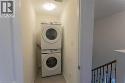Laundry room with stacked washer / drying machine and light tile patterned flooring - 