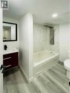 Bathroom featuring light wood-style flooring, vanity, and shower / bath combination - 