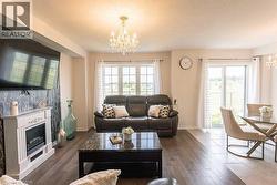 Living area featuring a chandelier, a glass covered fireplace, and dark wood-style floors - 