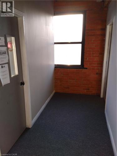 Hallway with brick wall and dark colored carpet - 12 Ferguson Avenue N, Hamilton, ON 