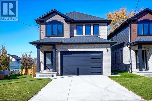 View of front of home featuring brick siding, a front yard, concrete driveway, a garage, and a shingled roof - 256 W King Street, Ingersoll, ON - Outdoor With Facade