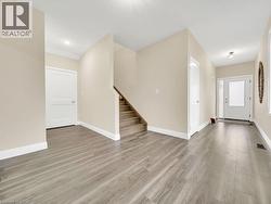 Unfurnished living room featuring light wood finished floors and stairs - 