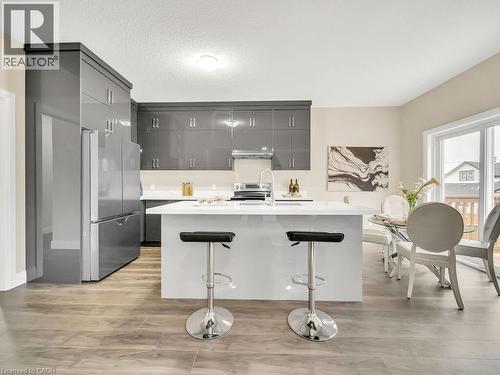 Kitchen with modern cabinets, stainless steel appliances, a kitchen island with sink, light wood-style flooring, and a kitchen breakfast bar - 256 W King Street, Ingersoll, ON - Indoor Photo Showing Kitchen With Upgraded Kitchen