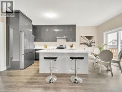 Kitchen with modern cabinets, stainless steel appliances, a kitchen island with sink, light wood-style flooring, and a kitchen breakfast bar - 