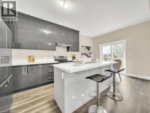 Kitchen featuring a kitchen bar, light wood finished floors, an island with sink, gray cabinetry, and modern cabinets - 256 W King Street, Ingersoll, ON - Indoor Photo Showing Kitchen With Upgraded Kitchen