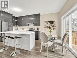 Kitchen with a kitchen island with sink, light wood-style floors, appliances with stainless steel finishes, a kitchen bar, and modern cabinets - 