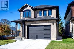 View of front of house featuring brick siding, a front yard, an attached garage, concrete driveway, and roof with shingles - 