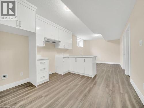 Kitchen featuring a peninsula, white cabinets, light wood-style flooring, light countertops, and under cabinet range hood - 256 W King Street, Ingersoll, ON - Indoor