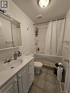 Full bath featuring shower / tub combo with curtain, vanity, and dark tile patterned flooring - 