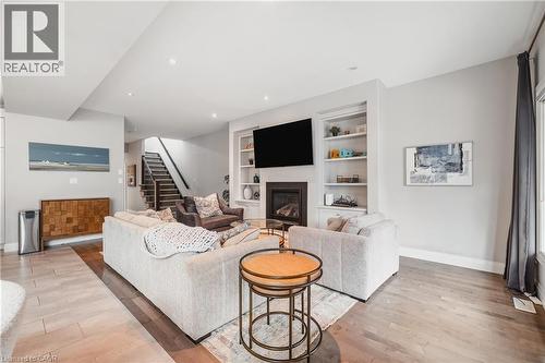Living room with a glass covered fireplace, light wood-style flooring, built in features, stairway, and recessed lighting - 346 Moorlands Crescent, Kitchener, ON - Indoor Photo Showing Living Room With Fireplace