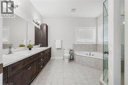 Bathroom featuring a bath, double vanity, light tile patterned flooring, and a stall shower - 