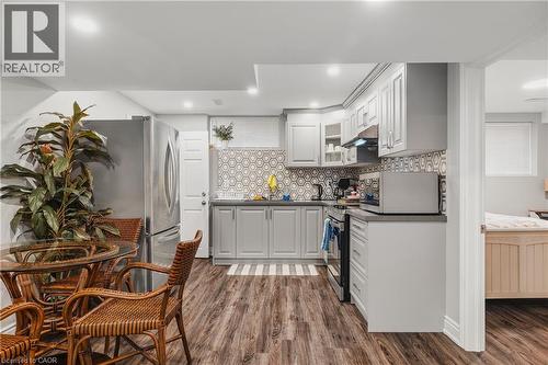Kitchen with dark countertops, decorative backsplash, dark wood-type flooring, appliances with stainless steel finishes, and glass insert cabinets - 346 Moorlands Crescent, Kitchener, ON - Indoor Photo Showing Kitchen With Upgraded Kitchen