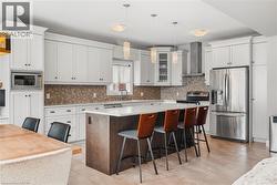 Kitchen with appliances with stainless steel finishes, a kitchen bar, a kitchen island, wall chimney range hood, and backsplash - 