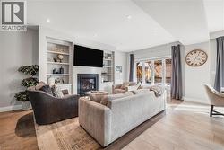 Living area with a glass covered fireplace, recessed lighting, light wood finished floors, and built in features - 