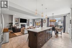 Kitchen with hanging light fixtures, a center island, a breakfast bar area, dark brown cabinetry, and a glass covered fireplace - 