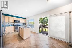 Kitchen featuring backsplash, appliances with stainless steel finishes, a kitchen island with sink, and light brown cabinets - 