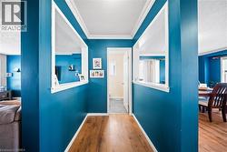 Hall featuring a textured ceiling, ornamental molding, wood finished floors, and plenty of natural light - 