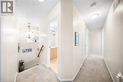 Hallway with light carpet, a textured ceiling, and a chandelier - 