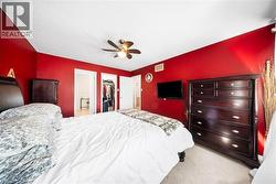 Bedroom featuring light carpet, ensuite bath, a ceiling fan, and a walk in closet - 