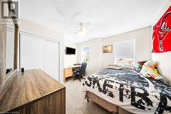 Bedroom featuring light carpet, a closet, a ceiling fan, a textured ceiling, and a desk - 