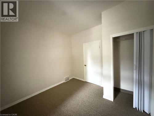 Unfurnished bedroom featuring dark colored carpet and a closet - 24 Somerset Avenue, Hamilton, ON - Indoor Photo Showing Other Room