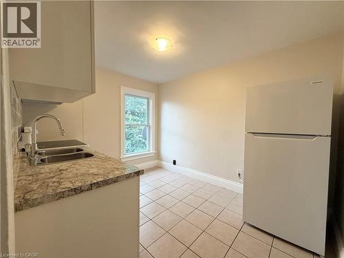 Kitchen featuring freestanding refrigerator, light countertops, and light tile patterned floors - 24 Somerset Avenue, Hamilton, ON - Indoor Photo Showing Kitchen With Double Sink
