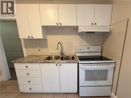 Kitchen featuring electric range, light countertops, white cabinetry, and light tile patterned floors - 24 Somerset Avenue, Hamilton, ON - Indoor Photo Showing Kitchen With Double Sink