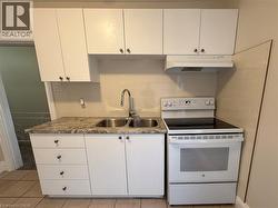 Kitchen featuring electric range, light countertops, white cabinetry, and light tile patterned floors - 